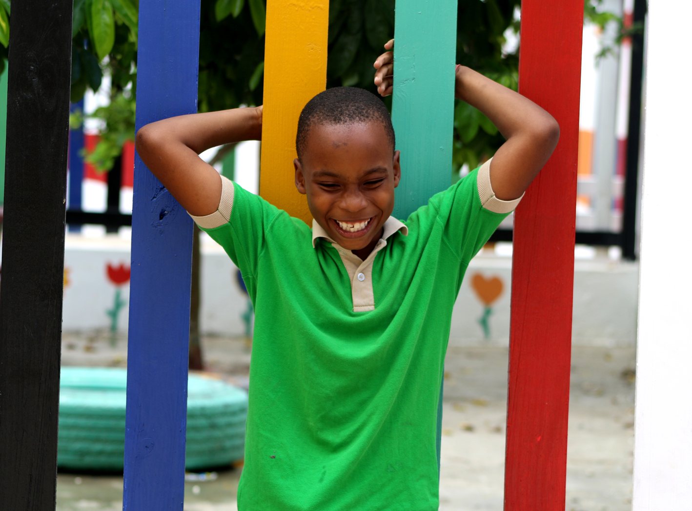 Estudiante sonriendo frente a la verja de colores de la escuela